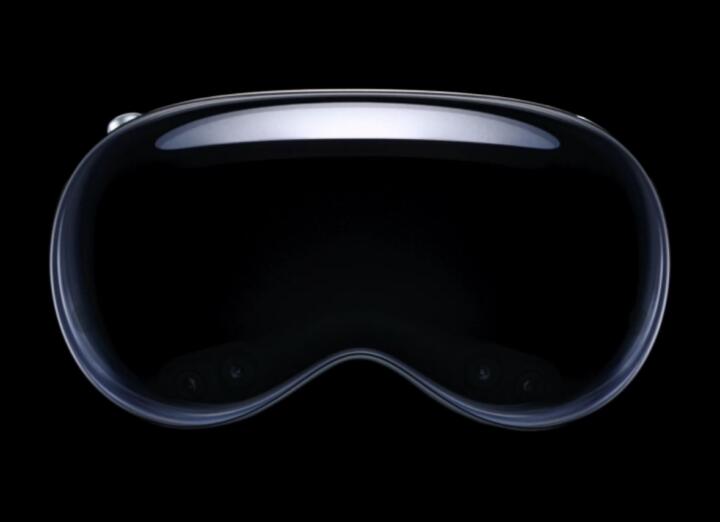 Apple Vision Pro headset floating against a black background, showing its curved glass front, the Solo Knit band across the top and the digital crown on the right